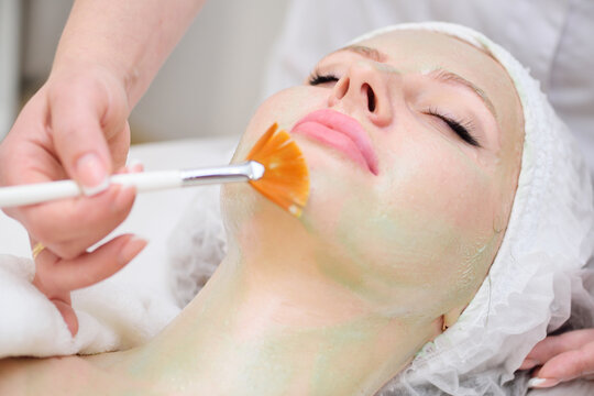 A cosmetologist performs an enzyme therapy procedure for a female patient.