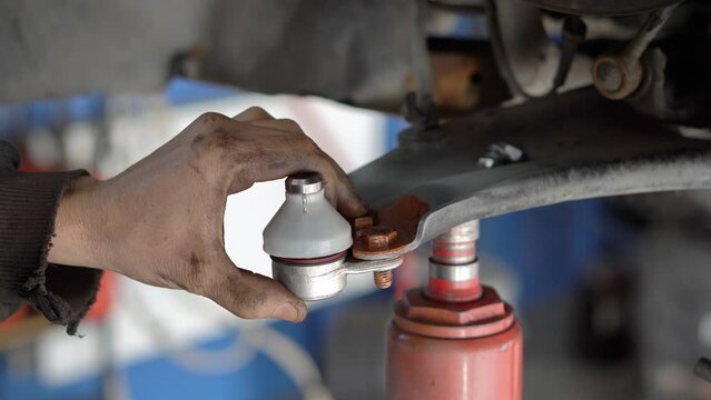Ball joint replacement in a car. Hand of Auto Mechanic or Car Mechanic Tighten Upper Arm Ball Joint Nut in Car or Auto Repair Shop