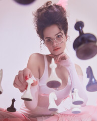 Beautiful young woman with chess pieces around, retro glasses and thoughtful expression. Promotion...