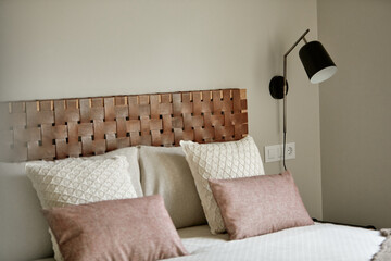 Modern bedroom interior with pillows on bed and stylish wall-mounted lamp.