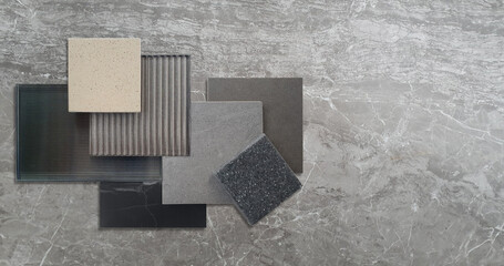 combination of interior material samples for modern loft style concept including corrugated glasses, grainy quartz, stone ceramic tiles, black marble placed on grey emperador marble background.