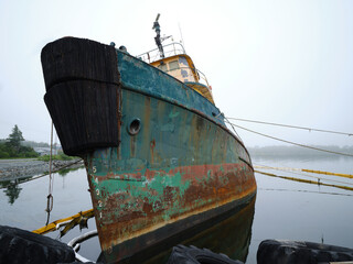 Large rusting tugboat listing and sinking on its starboard side in Hawbolt Cove in Halifax Nova Scotia - 731141380