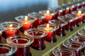 Many glasses with lit candles in a Catholic Chapel