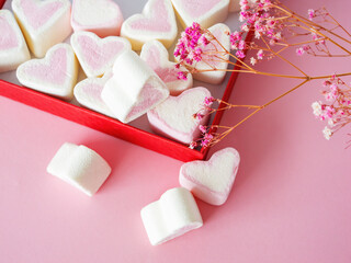 Lots of marshmallows in the shape of hearts in a red box on a pink background with copy space. Valentine's Day, Mother's Day, Father's Day, Wedding. Sweet confectionery product. Symbol of love