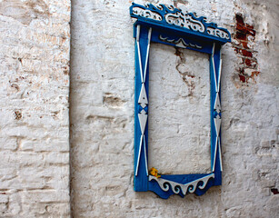 
An antique window frame is attached to the wall as a museum piece. The casing is carved and painted with blue and white paint.