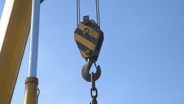 Mobile crane with hook and straps is raising work platform, basket.