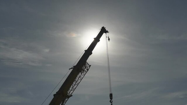 Mobile crane with hook and straps is raising work platform, basket.