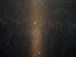 Snowflakes fly in the air illuminated by the sun.