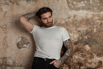 handsome muscular brutal hipster man with a hairstyle and beard with a tattoo in a white mock-up...