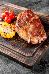 Grilled Ribeye Steak on wooden board, prime cowboy steak on dark background
