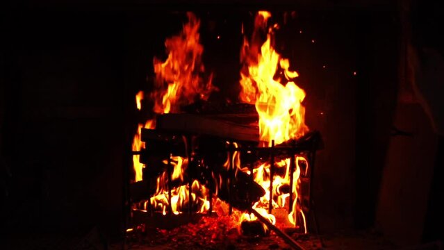 Man put wood into the fire and flames of fireplace. Slow motion video