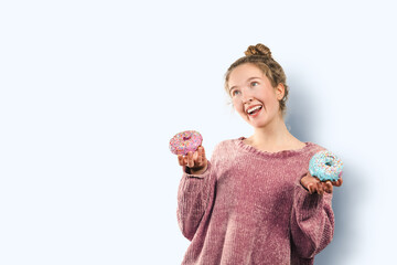 Happy joyful woman with delicious glazed doughnut laughs happily dressed in casual pink knitted...