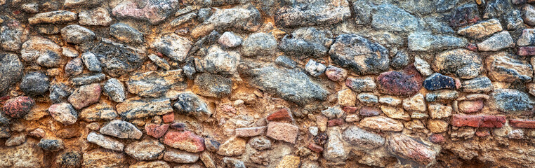 Panorama. Panoramic shot of an old wall made of large stones that is part of the walls of the citadel of Vejer de la Frontera, Spain. Architectural background. Stone background