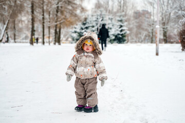 Fototapeta na wymiar Cute child toddler walks in a snowy winter park