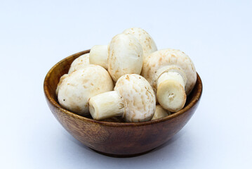 White mushrooms in a wooden bowl on white background 