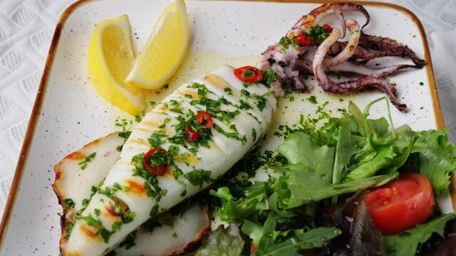Grilled squid and fresh salad on a plate rotate