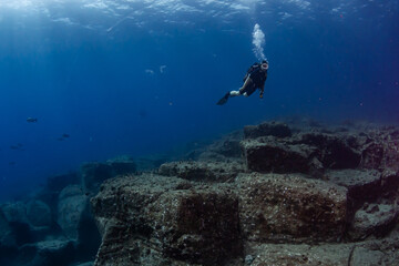 Female diver over rocky reef against blue background in Mauritius