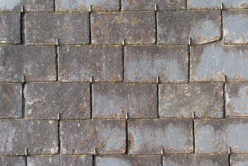 Old neglected slate roof tiles on a tenement house in France.