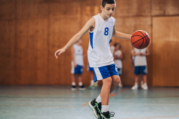 A junior basketball player is practicing basketball on court.