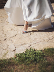 Legs of the bride in high heels. Wedding white shoes on the bride's feet. 