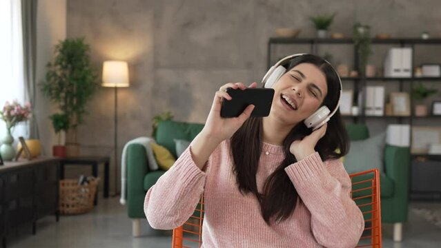 One woman with headphones at home listen music online happy smile sing