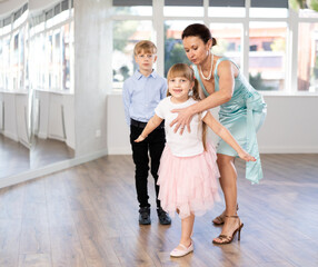 Woman teacher explains to teen students correct position during pair classical dance and rectify...