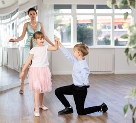 Preteen dancers rehearsing ballroom dance as couple under guidance of female coach in choreography...