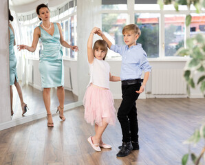 Couple of boy and girl kids twirling while taking waltz ballroom dancing lessons.