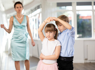 In well-lit dance studio, tween girl and boy focusing on perfecting rumba dance moves as couple...