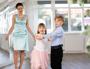 Small passionate ballroom enthusiasts, tween girl and boy practicing graceful waltz routine in...