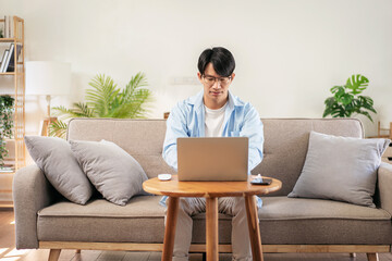 Businessman in casual is sitting comfortable sofa to thoughtful of idea for new business while using laptop