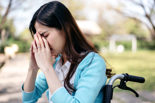 Woman on wheelchair concept, Young asian disabled woman on wheelchair in the garden and touching hands - Powered by Adobe