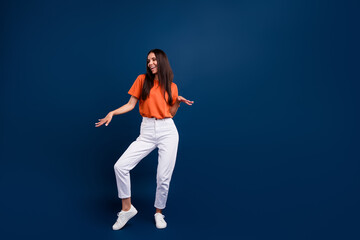 Full length photo of funky adorable woman dressed orange t-shirt dancing discotheque empty space isolated dark blue color background