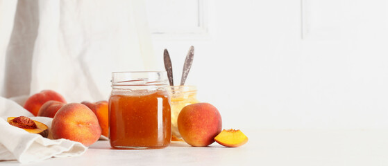 Jar with sweet peach jam on table against white background