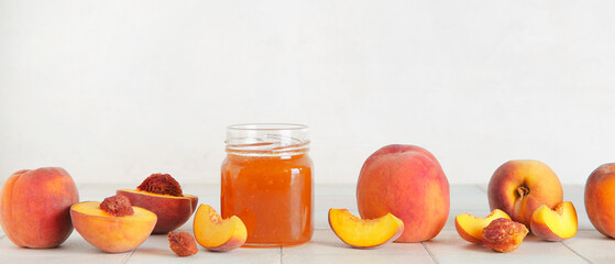 Fresh peaches and sweet jam in jar on table against white background