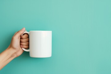 Female Hand Grasps White Thermal Mug Against Turquoise Background