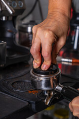 woman's hands pressing roasted and ground coffee to use in coffee maker