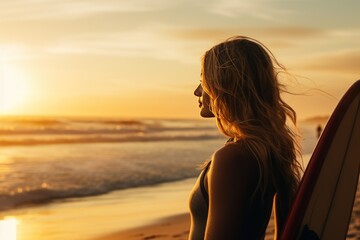 Fototapeta premium Beautiful girl at sunset on the beach. Young woman with a surfboard from behind