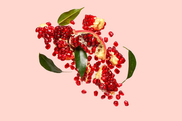 Flying fresh pomegranates with seeds and leaves on pink background