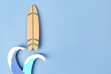 Creative composition with paper waves and mini surfboard on blue background