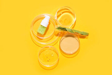 Petri dishes with herbs and bottle of cosmetic product on yellow background