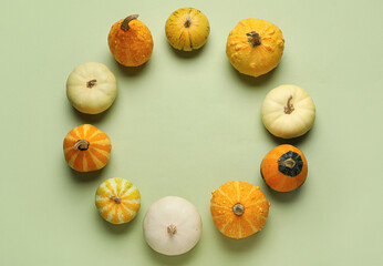 Frame made of different fresh pumpkins on green background