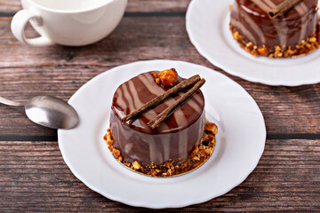 Fresh delicious chocolate souffle cake on white plate on wooden background. Caramel glaze and decoration add appeal and desire