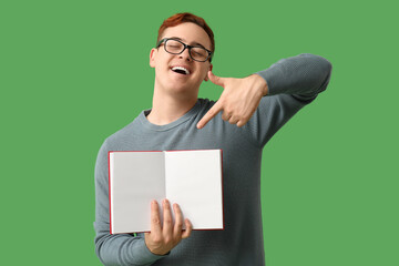 Young man pointing at blank open book on green background