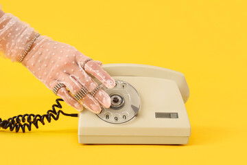 Woman with silver jewelry and telephone on yellow background, closeup