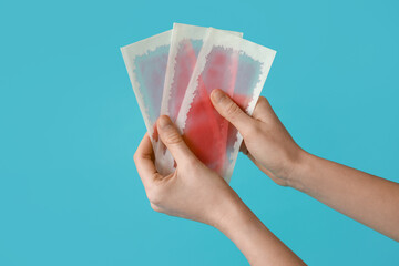 Female hands with wax strips on turquoise background - obrazy, fototapety, plakaty