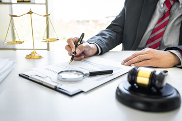 Male lawyer or judge working with contract papers, Law books and wooden gavel on table in courtroom, Justice lawyers at law firm, Law and Legal services concept