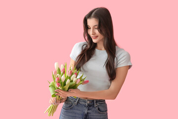 Pretty young woman with bouquet of beautiful tulips on pink background. International Women's Day