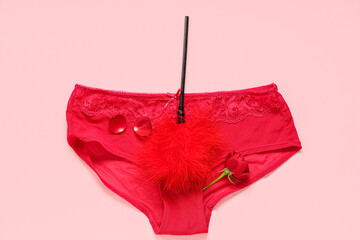 Sexy female panties, feather stick from sex shop and rose flower on pink background. Valentine's...