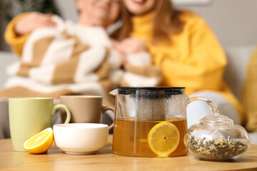 Teapot with cups and lemon on table in room, closeup